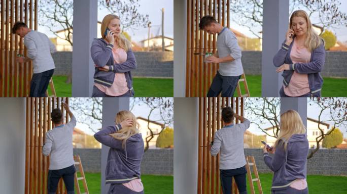 女人在手机上讲话，而男人在背景上画木架
