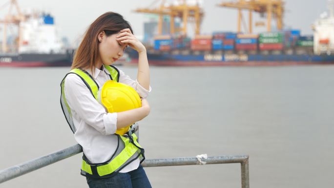 4K慢镜头：亚洲女工程师在建筑工地或造船厂从事建筑业或航运业的背景工作时情绪紧张。