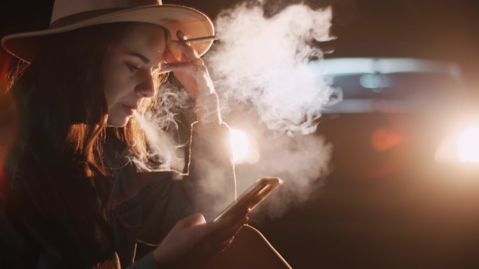 年轻女子在使用手机时吸烟