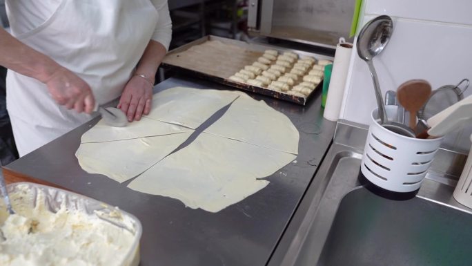 一位经验丰富的女面包师在厨房柜台上切新揉面团的特写视频