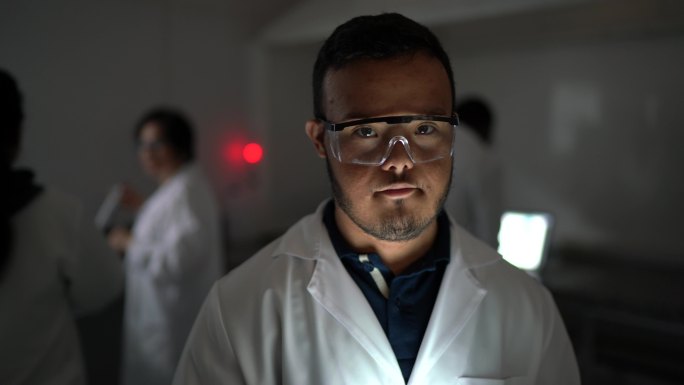 实验室里一位特殊需要的年轻科学家的肖像，背景中的同事
