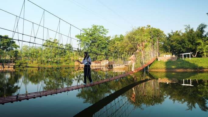 亚洲的孩子们在湖上的长袍桥上行走，带着水的倒影和生活方式的概念。