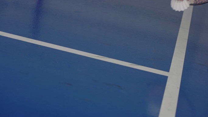 SLO MO：羽毛球运动员手持球拍，在体育馆地板上拿起羽毛球。