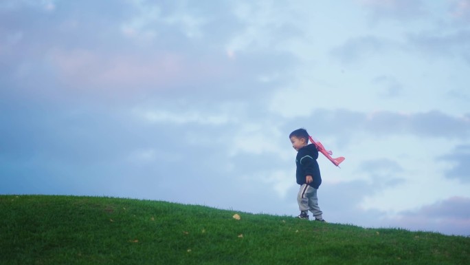 小孩草地扔飞机模型小孩奔跑儿童节快乐童年