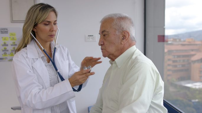 老年医学女医生用听诊器检查一名男性患者
