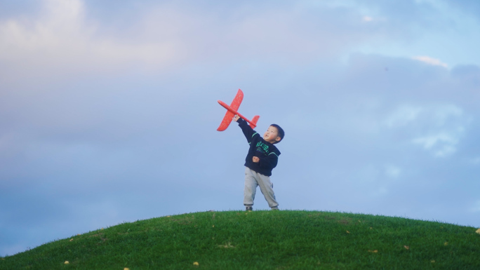 小孩草地扔飞机模型童年快乐时光小孩玩耍