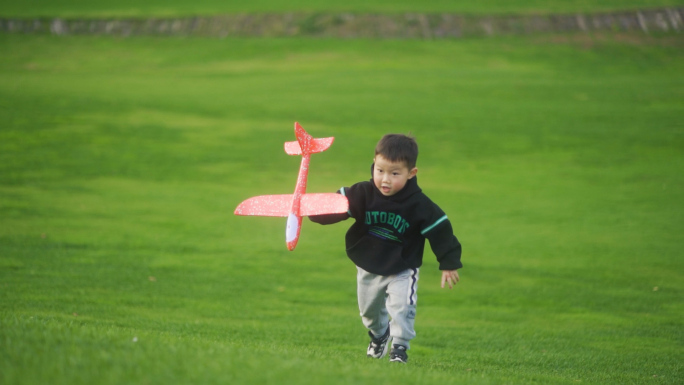 小孩拿着飞机模型草地奔跑欢乐童年时光儿童
