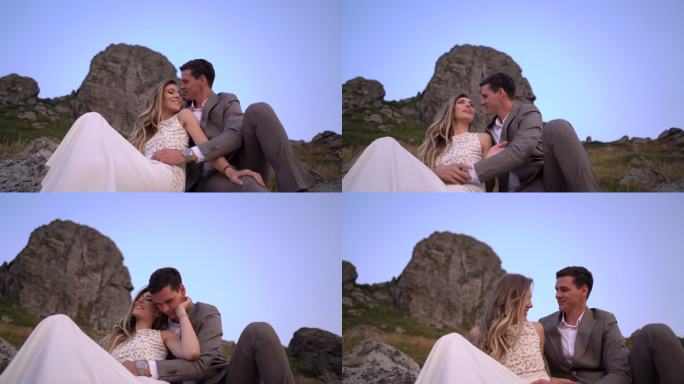 浪漫的新婚夫妇坐在山上的岩石上
