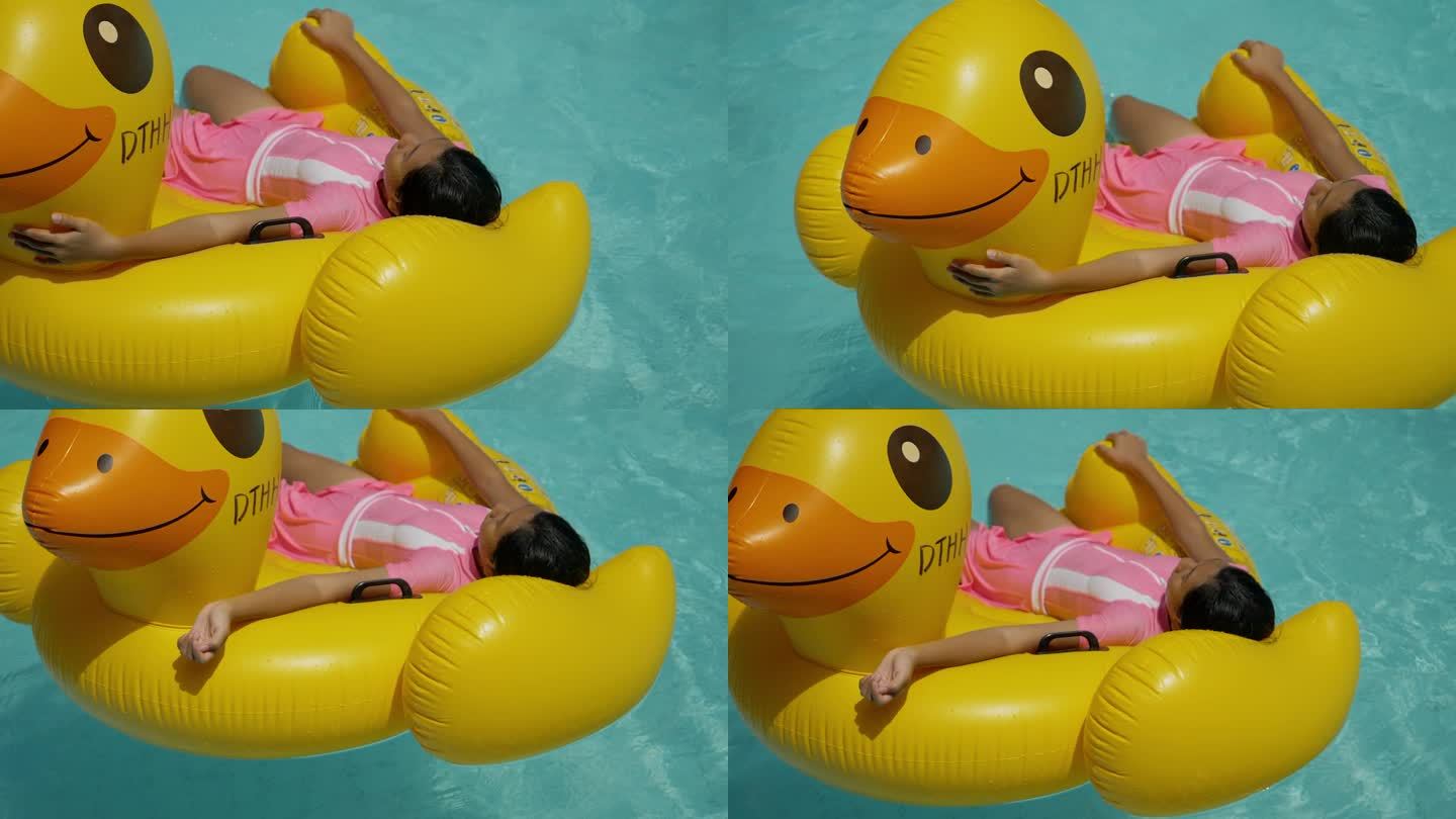快乐的亚洲女孩在与家人、生活方式理念一起度假时，在游泳池里的黄鸭橡皮筏上放松。