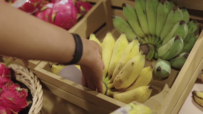 在零售店里，一只雄性手拿起一大串香蕉