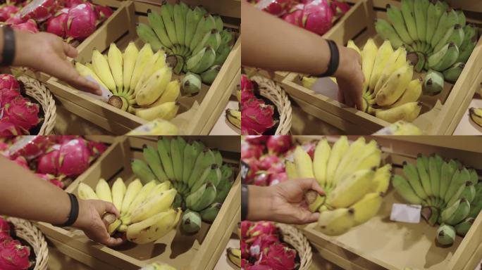 在零售店里，一只雄性手拿起一大串香蕉