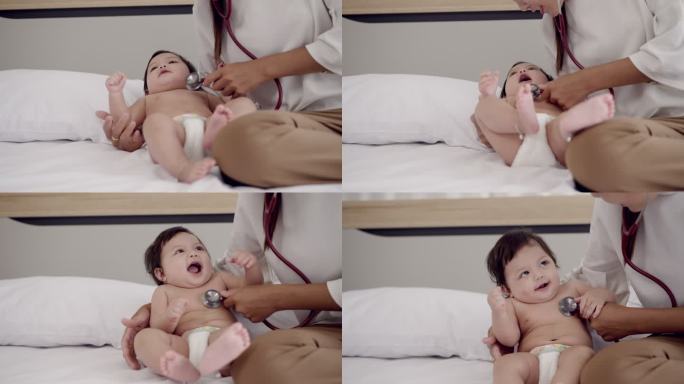 快乐的家庭时光。一位年轻的亚洲母亲手里拿着两岁的小女婴，手里拿着尿布，用听诊器听女儿的心率，和可爱的