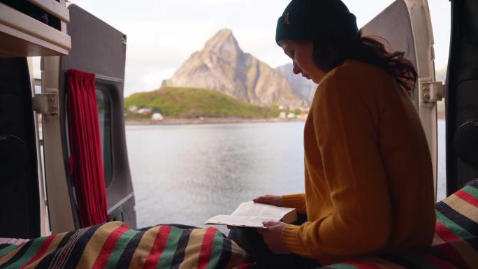 在罗弗顿岛的海边，女人在露营车上看书