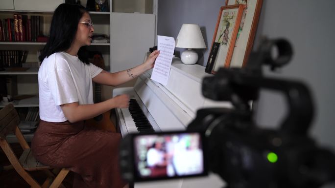 一位年轻的音乐艺术家正在录制关于如何弹钢琴的社交媒体教程