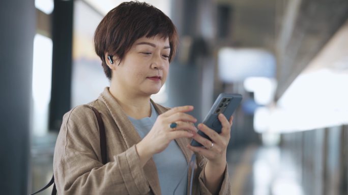 使用人脸识别技术的亚洲中国女子解锁手机并打开手机应用程序收听音乐