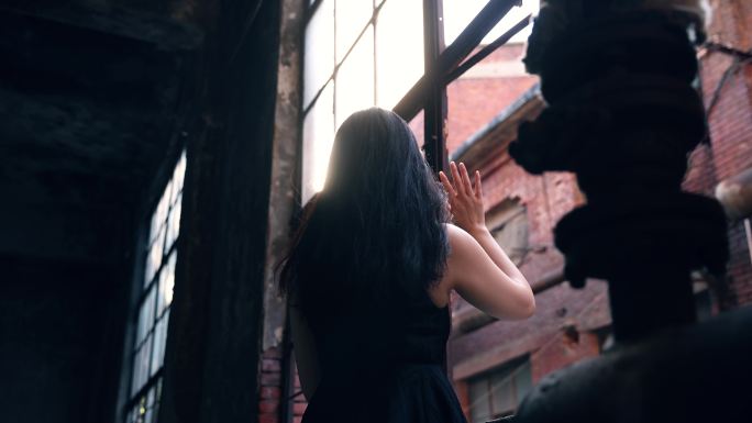 一个女人在废墟中望着旧窗户