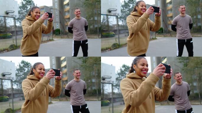 一名女子在城市的球场上拍摄朋友踢足球的照片