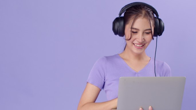 20多岁的亚洲女性通过耳机笔记本听音乐聊天，表达自己的快乐