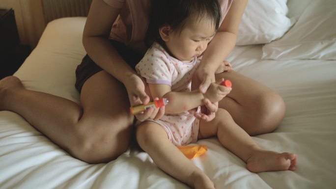 一位亚洲母亲给被蚊子叮咬的婴儿涂上了一种过敏药。
