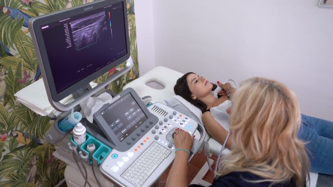 女医生用超声扫描仪检查患者甲状腺