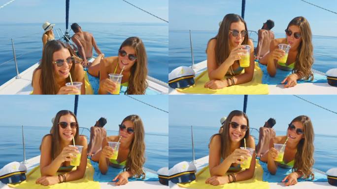 SLO MO两位年轻女性朋友在海上游艇上晒太阳的照片