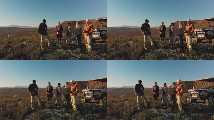 Safari导游和团队在阳光明媚的山丘上交谈和喝咖啡