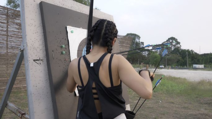 近距离观看在靶场练习射箭的迷人亚洲女性。