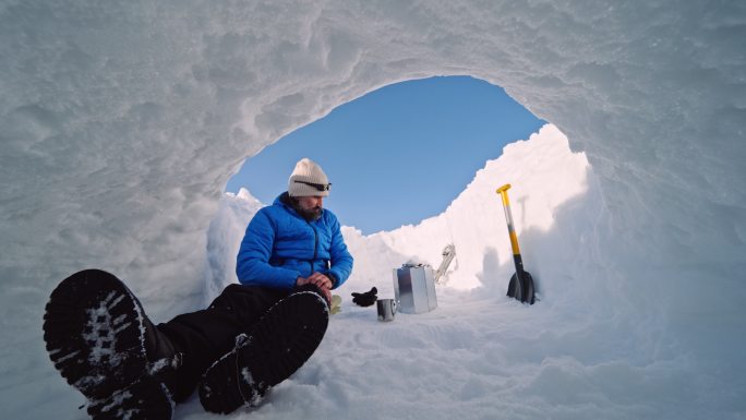 成熟的游客在雪地里喝咖啡。在大自然中独自在冬天的山上露营。