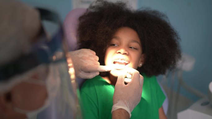 牙医检查坐在牙科椅上的儿童的牙齿