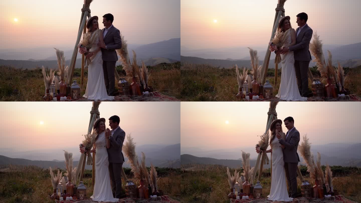 日落时分，幸福的新婚夫妇站在山上拥抱