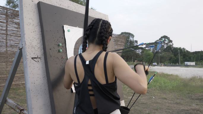 特写在靶场练习射箭的迷人亚洲女性，她很高兴自己击中了目标。