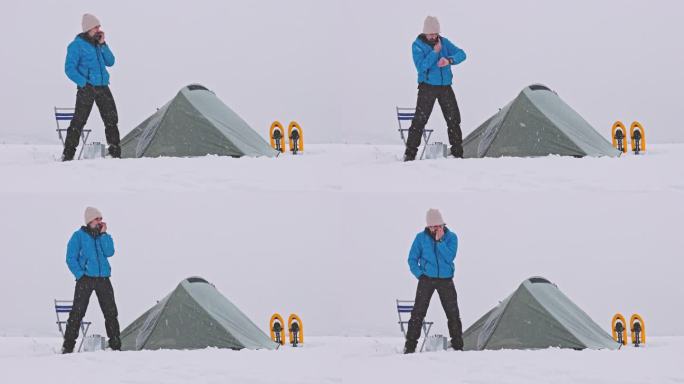 成熟的游客在大自然中独自在冬天的山上露营时使用电话。