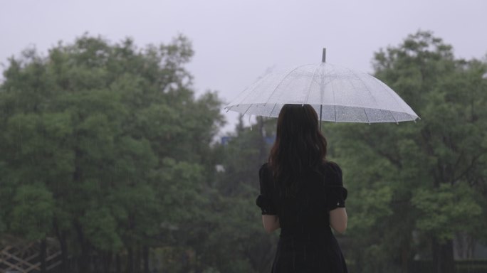 女生漫步雨中打伞背影回头看