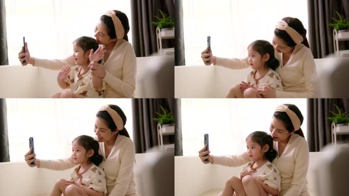 母亲和幼儿女儿通过手机视频通话技术与父亲交谈。
