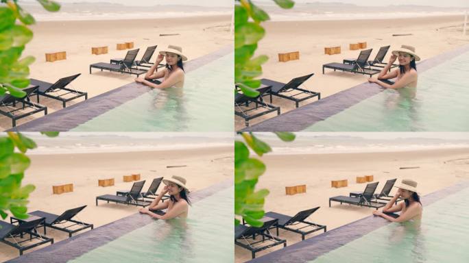 海滩上的豪华旅游女性坐在泳池边的沙滩椅上。