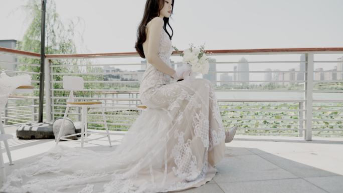 在婚礼现场，一位美丽的亚洲年轻女子身着婚纱，手持一束鲜花，坐在遮阳伞下