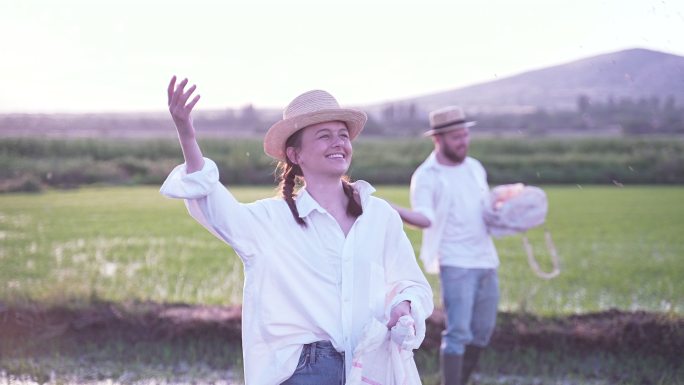 可爱的女农民和她的男朋友一起在稻田里播种水稻