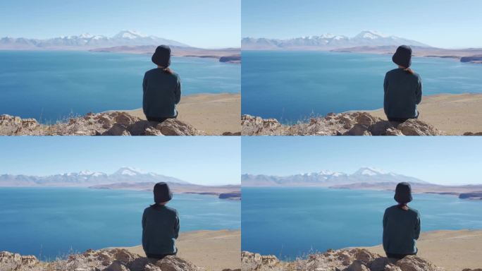 女孩坐在玛旁雍错湖边眺望纳木那尼峰