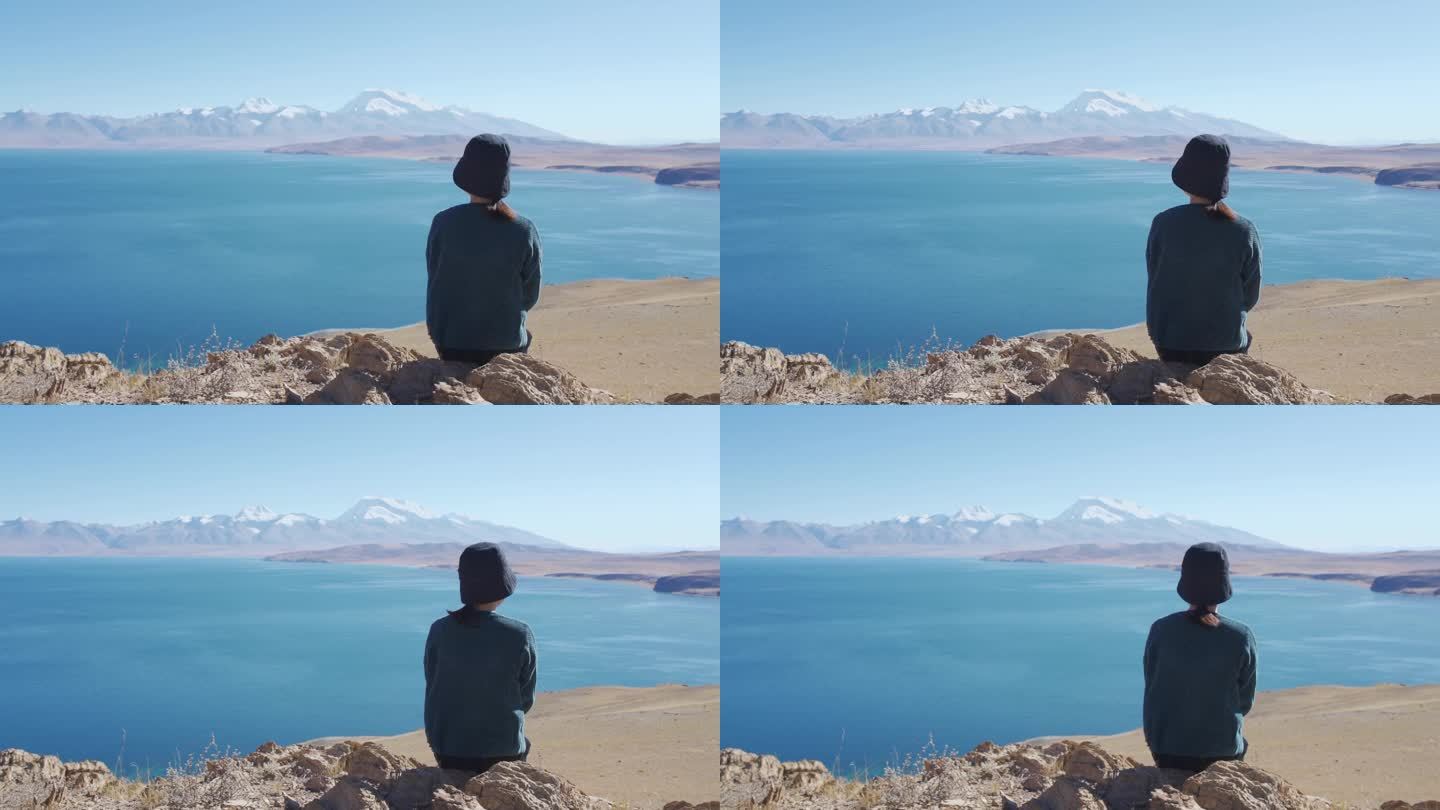 女孩坐在玛旁雍错湖边眺望纳木那尼峰