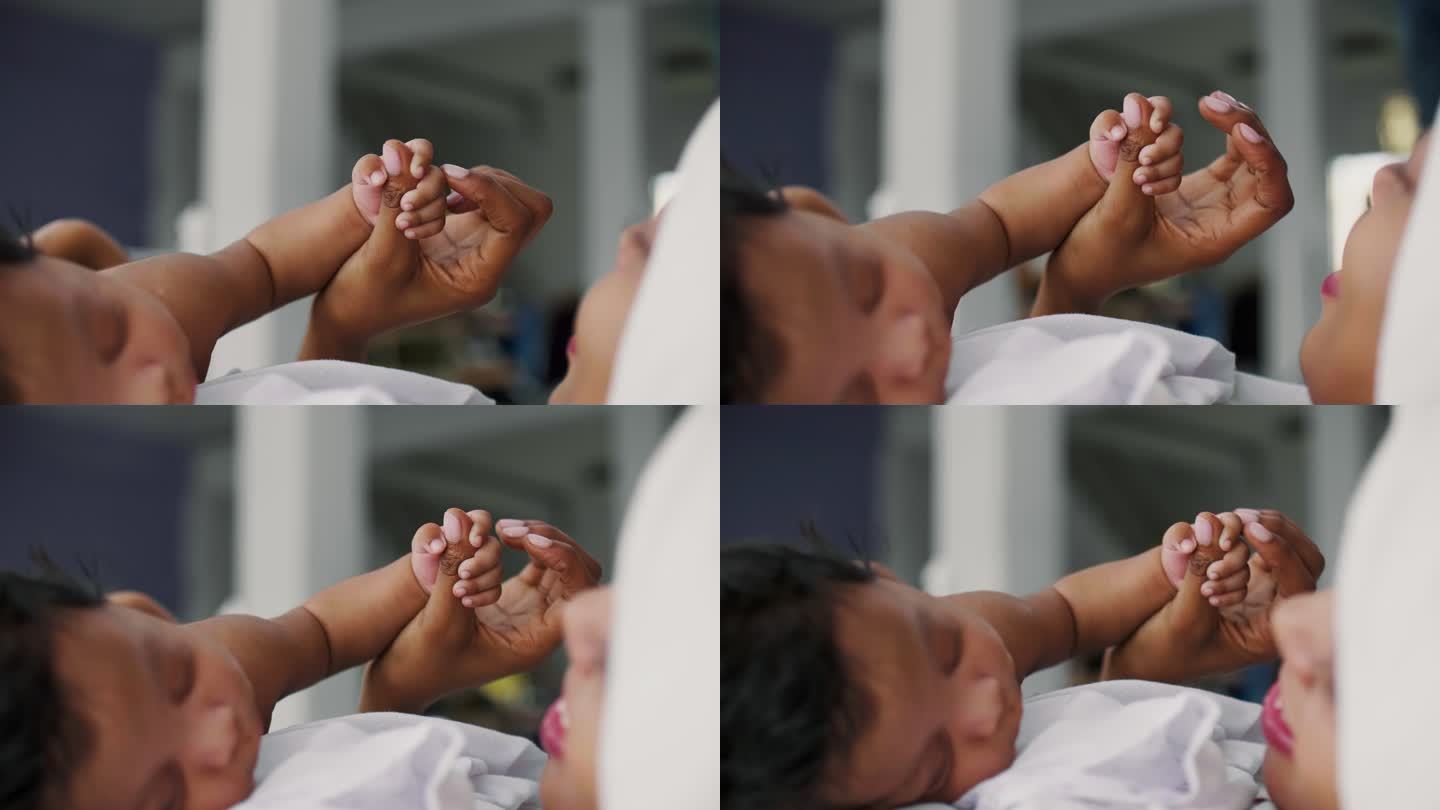 婴儿儿子紧握母亲的手指