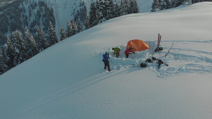 一组滑雪者在雪山帐篷周围的空中无人机拍摄