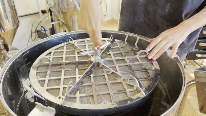 酿酒大师将盖子插入自动壶中，用于精酿啤酒生产。