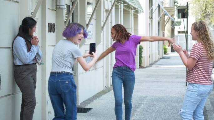 青少年女孩用智能手机拍摄朋友