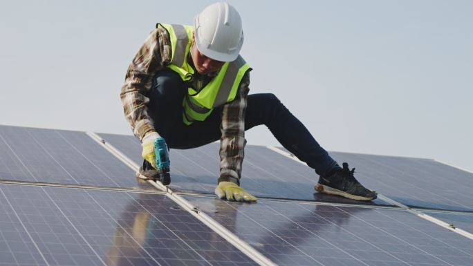 亚洲年轻男性在屋顶光伏太阳能电站的光伏板上工作