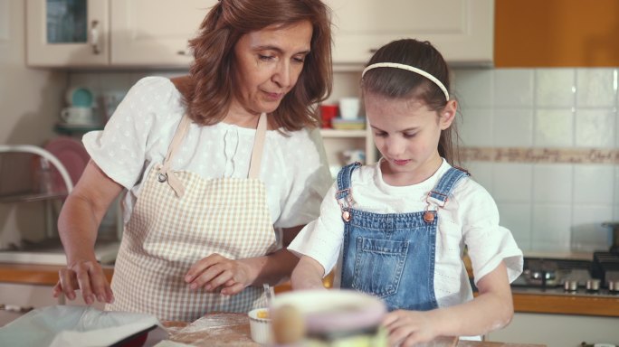 女孩喜欢和奶奶在一起，她和奶奶在厨房里做甜羊角面包。