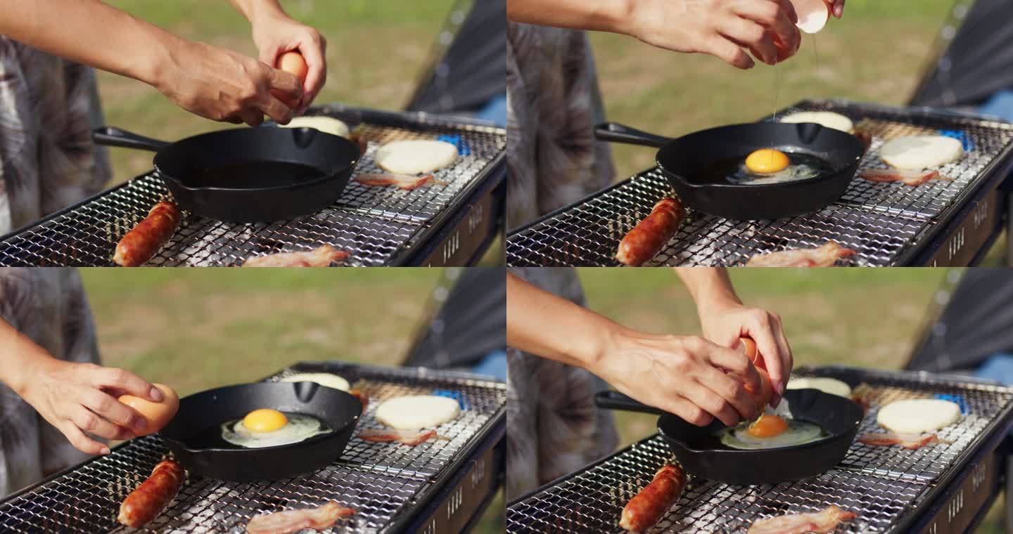 在烤肉上用手将鸡蛋放入煎锅的特写