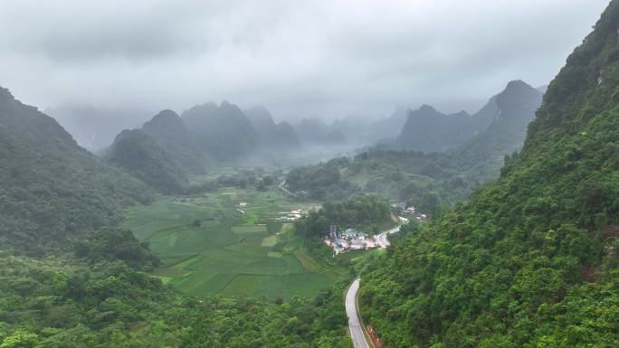 无人机在雾蒙蒙的蜿蜒山路上飞行，靠近雾蒙蒙的雨林树木。电影镜头鸟瞰雄伟的热带山脉景观。越南北部