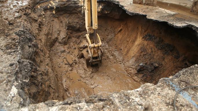 挖掘机挖掘街道下方断裂的输水干管