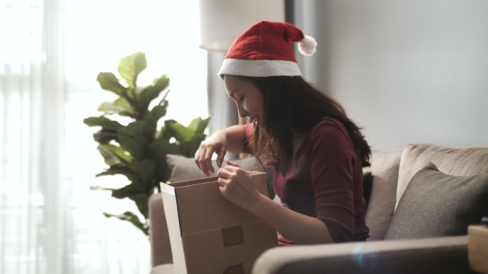 亚洲女性消费者打开纸箱在圣诞节收到邮包