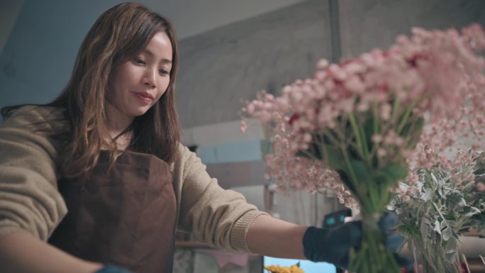 亚洲华人女花商，小企业主，在花店布置花束。经营小企业的日常生活